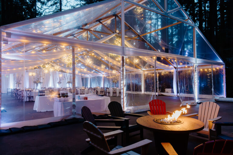 String-lit pavilion at night with a fire pit and lounge seating at Nestldown